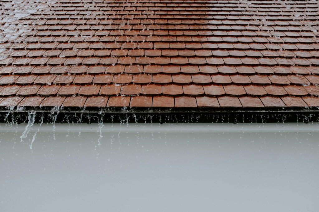 Rainwater running down overlapping roof tiles during a storm